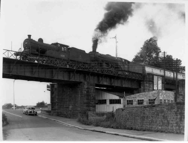 Steam train on bridge, by North Bridge Garage